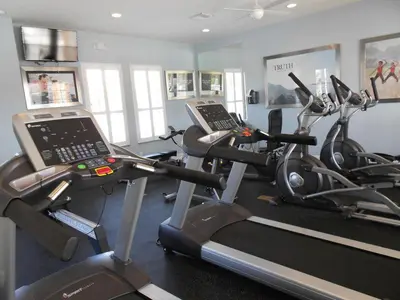 a gym with two tread machines and a laptop on a treadmill at 3 bedrooms pool home Hidden Forest Resort Amenities in Orlando