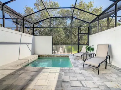 a swimming pool in a glass house with two chairs at 3 bedrooms pool home Hidden Forest Resort Amenities in Orlando