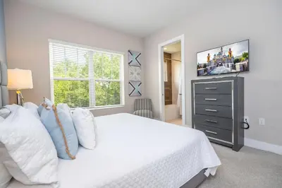 a bedroom with a white bed with a television on the wall at Gorgeous 4 Suites DREAM Villa 5 min to Disney in Orlando