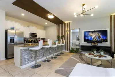 a kitchen with a bar with white chairs and a counter at Amazing Unbeatable Experience Themed Home w/ Private Pool and Resort in Kissimmee
