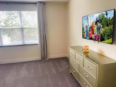 a bedroom with a dresser and a flat screen tv at 3 bedrooms pool home Hidden Forest Resort Amenities in Orlando