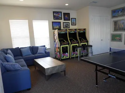 a living room with a ping pong table and four video games at 3 bedrooms pool home Hidden Forest Resort Amenities in Orlando