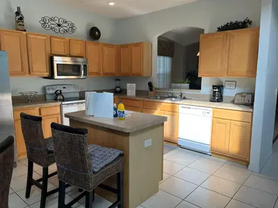 a kitchen with wooden cabinets and a island with bar stools at S890SB - 12 guests - 6 beds in Kissimmee
