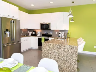 a kitchen with white cabinets and a granite counter top at Stylish 3-BR with Private Pool & Conservation View in Orlando