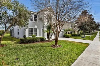 a white house with a tree in the yard at Themed Luxury 6BR Getaway with Resort Amenities in Orlando