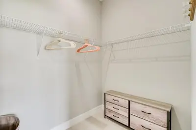 a bedroom with white walls and a wooden dresser at 3 Mi to Lakefront Beach St Cloud Apt in Ashton