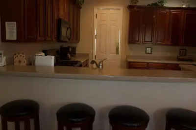 a kitchen with wooden cabinets and bar stools at Princess Hideaway in Orlando