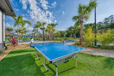 a ping pong table in a yard with palm trees at Charming Mickey-Themed Home Prime Location in Kissimmee