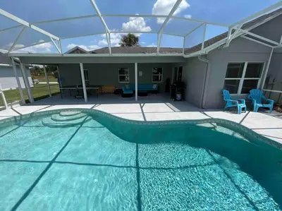 a swimming pool in front of a house at Luxury Waterfront 3b2b Heated Pool , Game Room , Piano House in Kissimmee