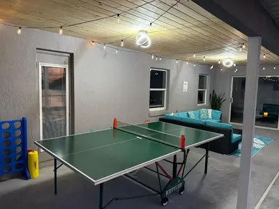 a room with a ping pong table and a couch at Luxury Waterfront 3b2b Heated Pool , Game Room , Piano House in Kissimmee