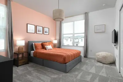 a bedroom with a bed with orange sheets and a window at Chic & Spacious Best Vacation Home in Kissimmee