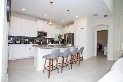 a kitchen with white cabinets and bar stools at Stunning 5BR Home - Your Dream Getaway in Kissimmee