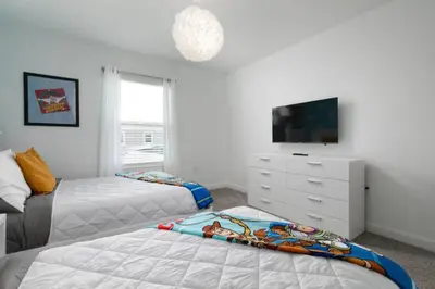 a bedroom with two beds and a tv and a dresser at Chic Retreat - Unforgettable Stay in Kissimmee