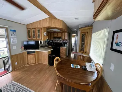 a kitchen and dining room with a wooden table at 15 min to Disney World, Self-check-in, Full Kitchen in Kissimmee