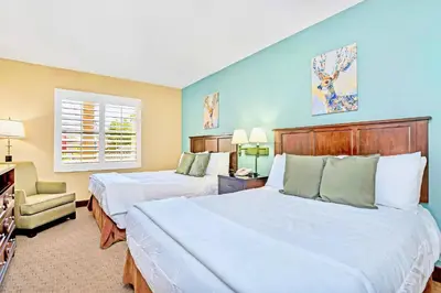a hotel room with two beds and a chair at 1BR Condo - Two Queens Arcade Pool - Near Disney in Orlando
