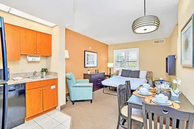 a kitchen and a living room with a table and chairs at 1BR Condo - Two Queens Arcade Pool - Near Disney in Orlando