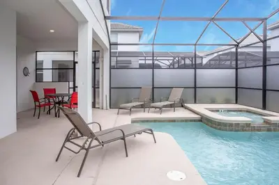 a patio with a pool and chairs and a table at Home 6BR - Prime Location in Kissimmee