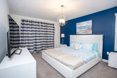 a bedroom with a bed with blue walls and a tv at Home 6BR - Prime Location in Kissimmee