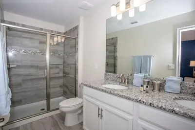 a bathroom with a toilet and two sinks and a shower at Home 6BR - Prime Location in Kissimmee