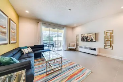 a living room with a blue couch and a glass table at Ultimate Getaway - Your Best Vacation Home in Orlando