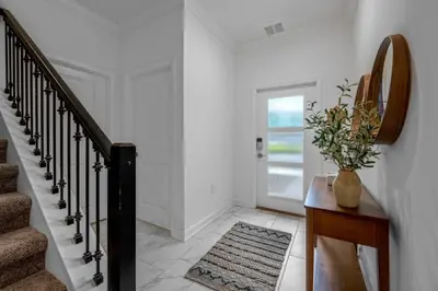 a white hallway with stairs and a vase of flowers on a table at Stunning Themed Home Private Pool Ideal Location in Kissimmee