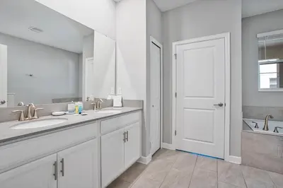 a white bathroom with two sinks and a white door at New Home 8 Bedrooms and 5 Bathrooms At Storey Lake in Kissimmee