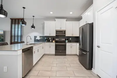 a kitchen with white cabinets and stainless steel appliances at New Home 8 Bedrooms and 5 Bathrooms At Storey Lake in Kissimmee