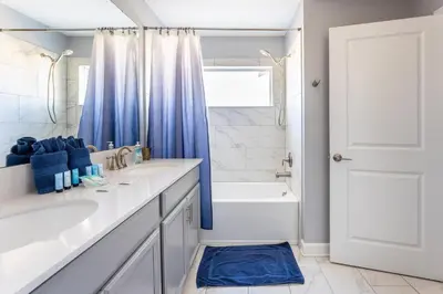 a bathroom with a white sink and a blue shower curtain at Family Retreat near Disney with Pool & Hot Tub! in Kissimmee