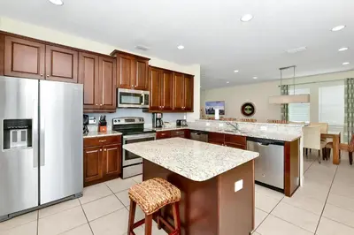 a kitchen with wooden cabinets and a white refrigerator at Lively Home Near Disney With Private Pool, Game And Themed Rooms With Waterpark & Resort Access At Encore Resorts Reunion - 670La in Kissimmee