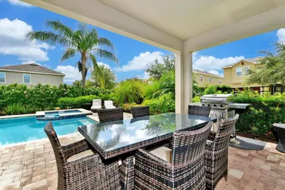 a patio with a table and chairs and a swimming pool at Lively Home Near Disney With Private Pool, Game And Themed Rooms With Waterpark & Resort Access At Encore Resorts Reunion - 670La in Kissimmee