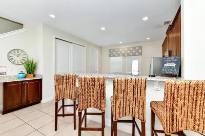 a kitchen with a bar with chairs and a clock at Lively Home Near Disney With Private Pool, Game And Themed Rooms With Waterpark & Resort Access At Encore Resorts Reunion - 670La in Kissimmee