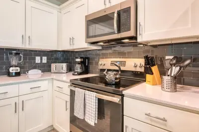 a kitchen with white cabinets and a stove top oven at Urban Elegance - Modern Retreat in Kissimmee