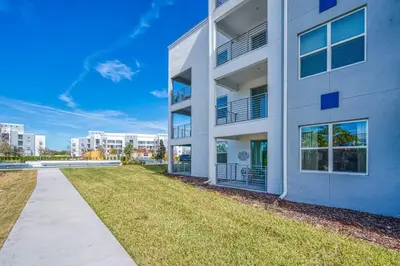 an apartment building with a grass yard in front of it at Urban Elegance - Modern Retreat in Kissimmee