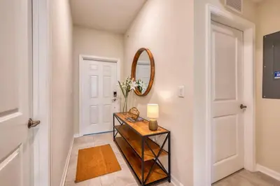 a hallway with a mirror and a table with a lamp at Urban Elegance - Modern Retreat in Kissimmee