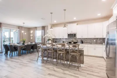 a kitchen with white cabinets and a table and chairs at Chic Luxury Haven - Unforgettable Retreat in Kissimmee