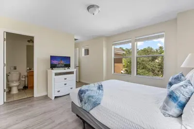 a white bedroom with a bed and a television at Enjoy the Large Pool - 6BR BL220 in Kissimmee