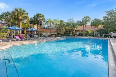 a large blue swimming pool with chairs and umbrellas at Spectacular House with 3BR - Private Pool, BBQ - Minutes from Disney! in Kissimmee