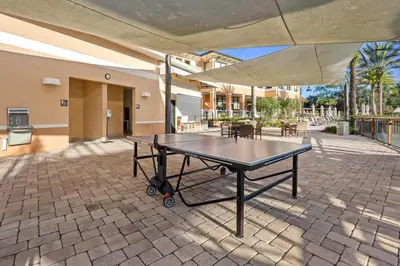 a ping pong table on a brick patio with an umbrella at 4 BR Hot Tub Cozy Decor @ Regal Oaks RO2761N in Kissimmee
