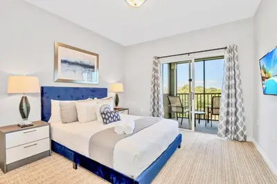 a bedroom with a blue bed and a balcony at Near Disney - 3BR Condo - Pool and Games in Orlando