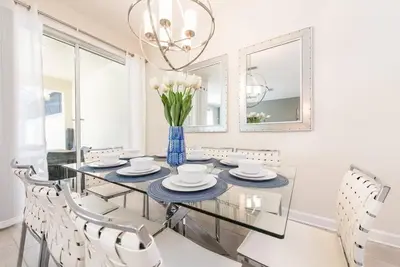 a dining room with a glass table and white chairs at Themed 4BR Home-Mickey & Star Wars Pool Spacious in Kissimmee