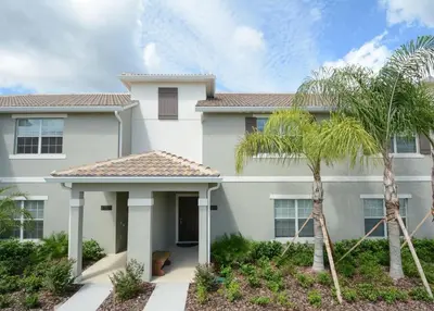 a white house with palm trees in front of it at Charming 4 BDR townhome at Storey Lake Resort in Kissimmee