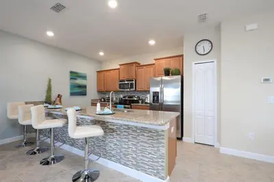 a kitchen with a counter with chairs and a refrigerator at Charming 4 BDR townhome at Storey Lake Resort in Kissimmee