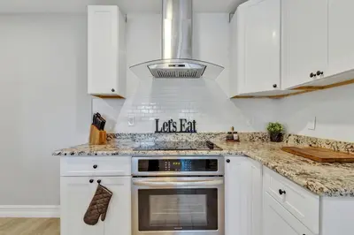 a kitchen with white cabinets and a stove top oven at Modern Lake Front Casita near Winter Park! in Orlando