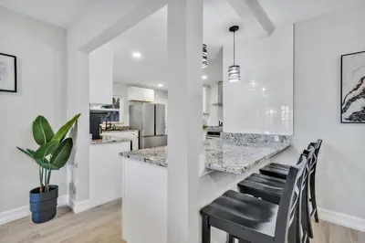 a kitchen with white walls and a bar with black chairs at Modern Lake Front Casita near Winter Park! in Orlando