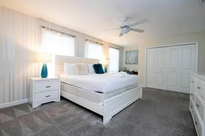 a bedroom with a white bed and a ceiling fan at Modern Marvel-Spacious, Themed, Fun-Filled in Kissimmee