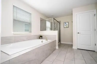 a white bathroom with a tub and a window at Modern Marvel-Spacious, Themed, Fun-Filled in Kissimmee