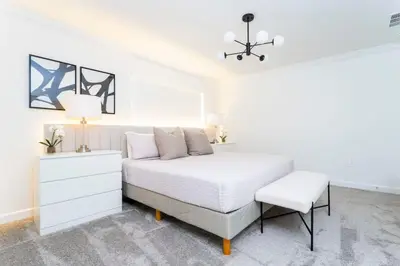 a white bedroom with a bed and a chair at Chic Modern Marvel, Themed Beds, Private Pool in Kissimmee