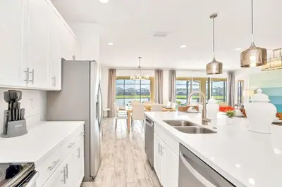 a kitchen with white cabinets and a dining room at Upstay Lakeside 10 Bedroom Home with Pool Private Cinema & Game Room in Kissimmee