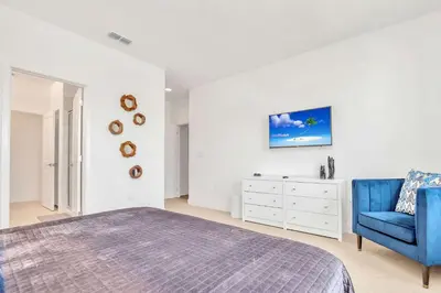 a bedroom with a bed and a blue chair at Upstay Lakeside 10 Bedroom Home with Pool Private Cinema & Game Room in Kissimmee