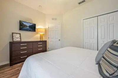 a bedroom with a white bed and a wooden dresser at Remodeled Gem - Comfort & Location in Kissimmee